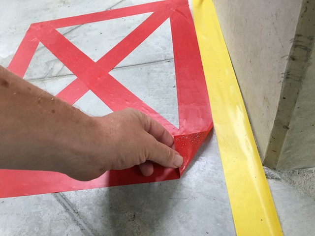 Detailaufnahme der manuellen Entfernung von rotem Markierungsband